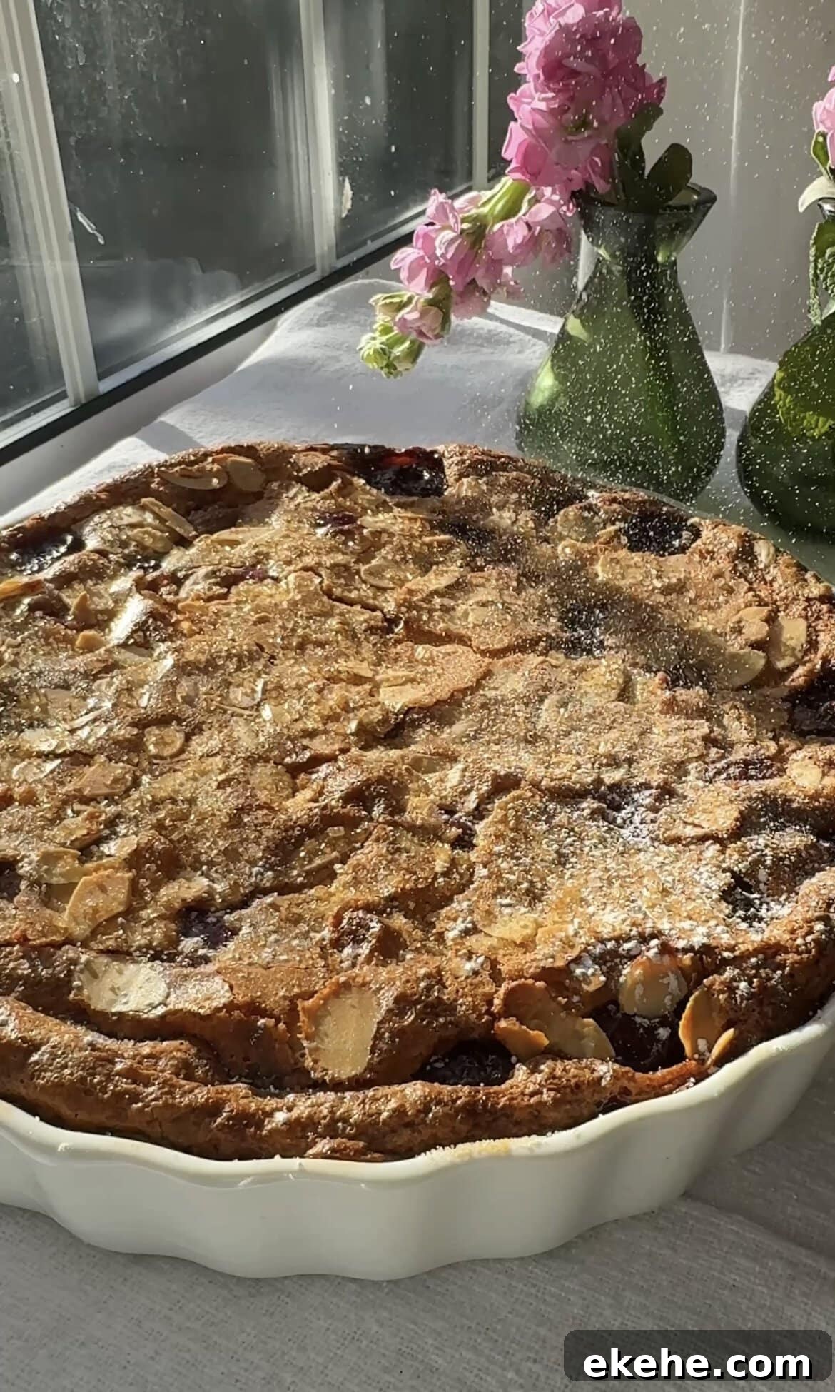 dusting clafoutis aux cerises with icing sugar.