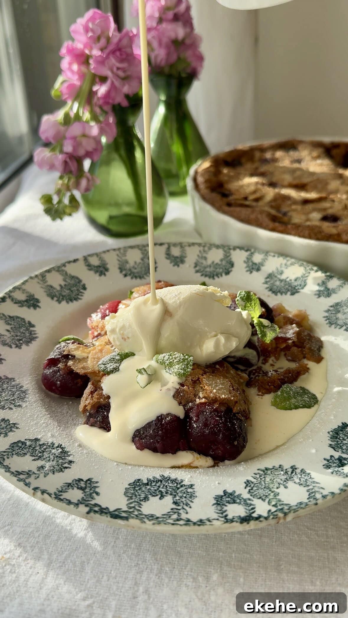 clafoutis aux cerises in bowl pouring cream over the top.