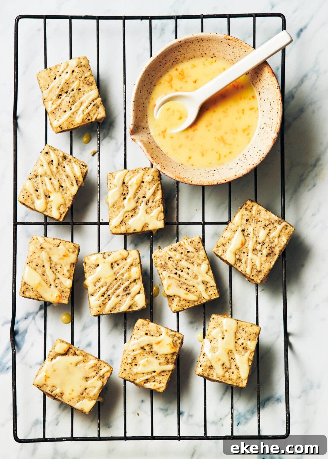 Best Earl Grey Shortbread cookies on a cooling rack with a bowl of orange royal icing.