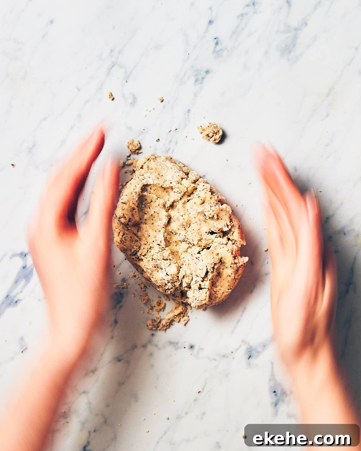 Hands gently kneading best earl grey shortbread dough on marble counter.