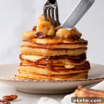 Fluffy banana foster pancakes topped with caramelized bananas and maple butter sauce and no rum.