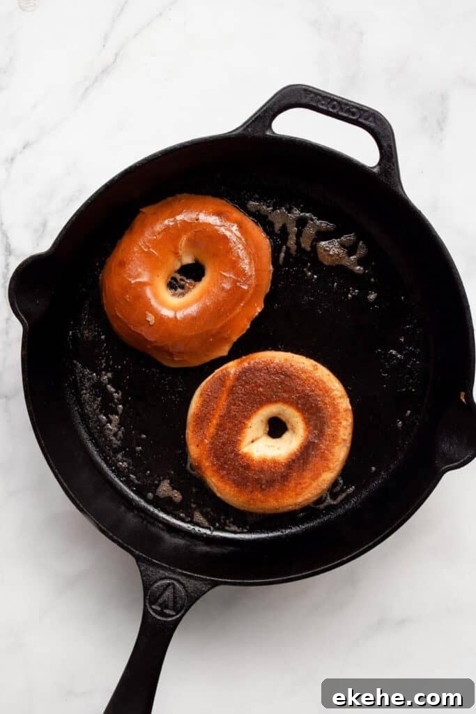 cooking french toast bagels in a buttery cast iron skillet