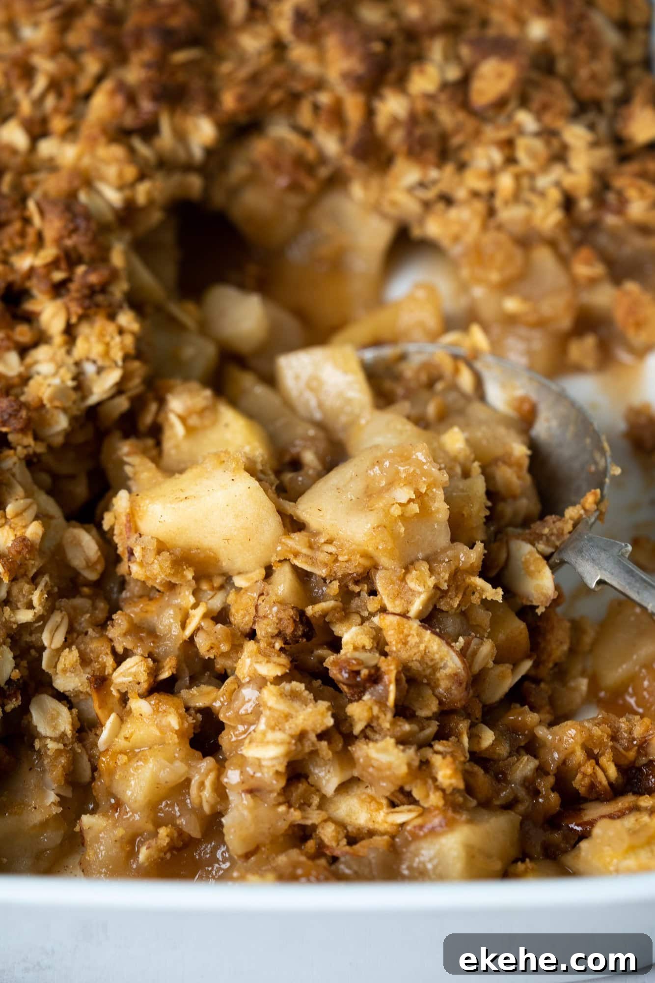 Close up image showing crispy oats, almond flakes and cooked apples in apple crisp