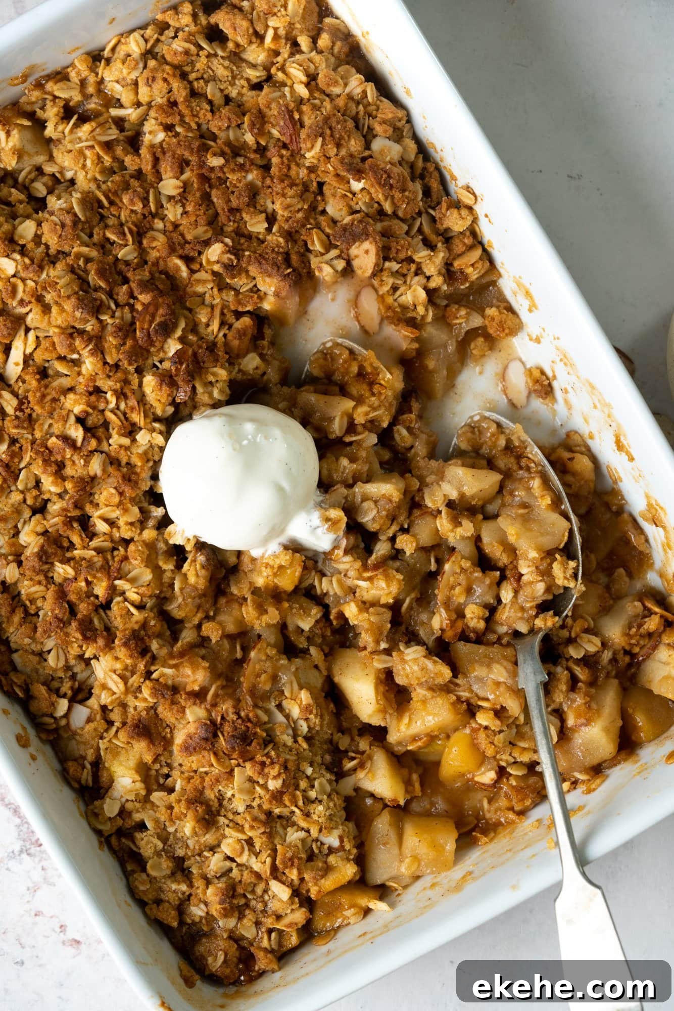 Apple crisp in a baking tray with a scoop of vanilla ice cream on top