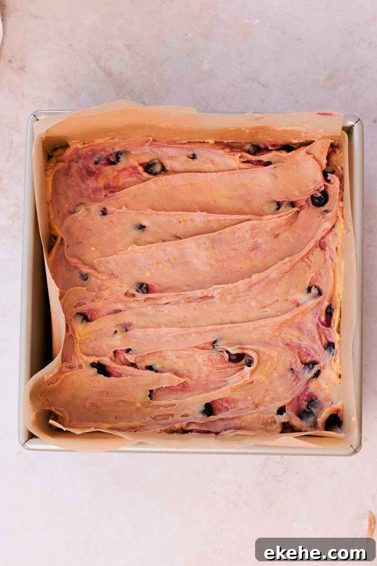 blueberry brownie batter in square pan with parchment paper