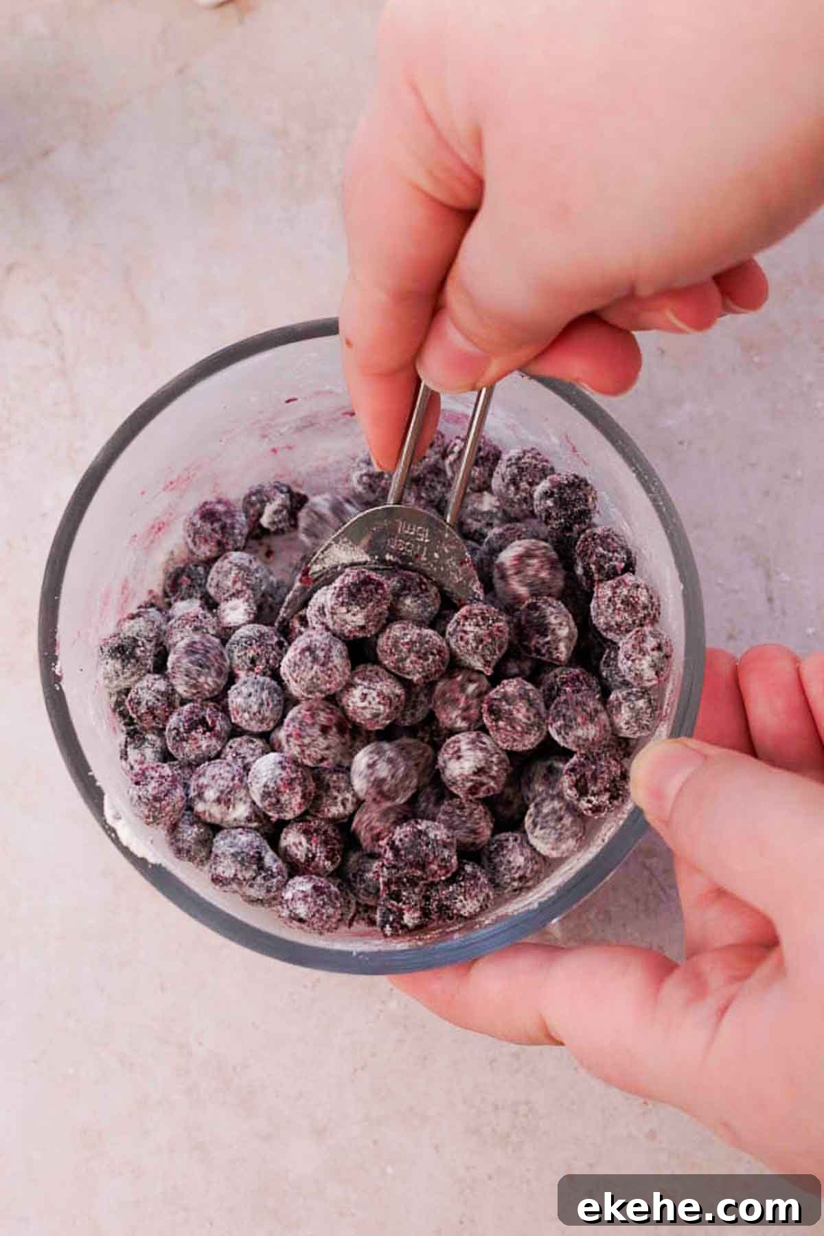 mixing blueberries and flour in a small glass bowl