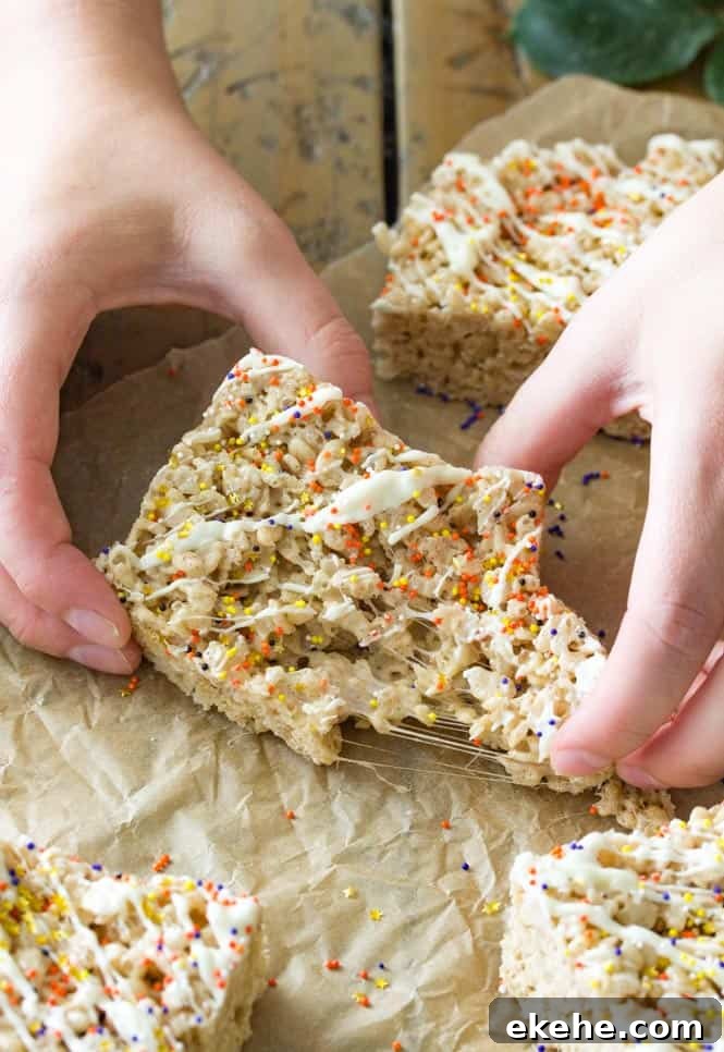 Hand pulling apart pumpkin spice rice krispie treats