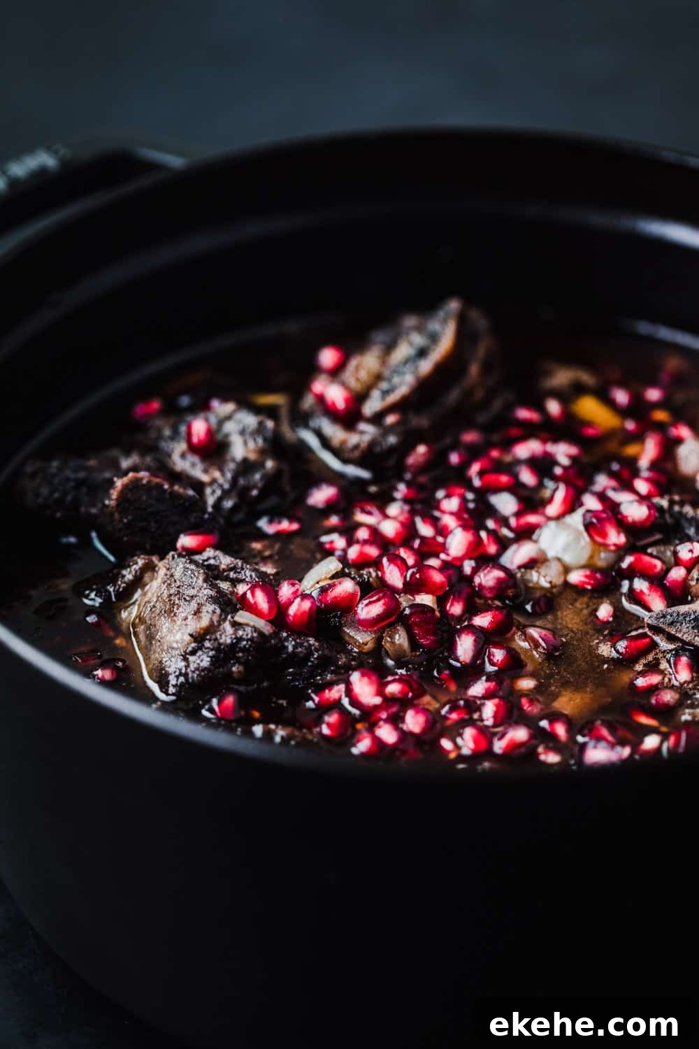 side angle shot red wine braised short ribs, with pomegranate arils.