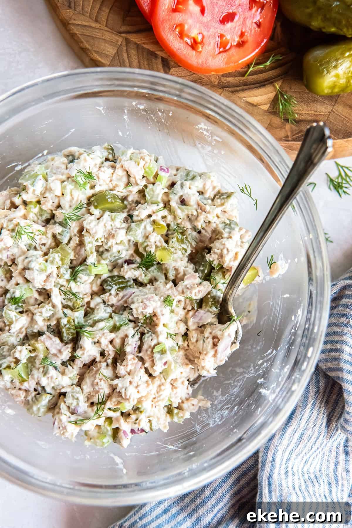 Dill pickle tuna salad in a glass bowl with visible chunks of albacore tuna, pickles, celery, and fresh dill.