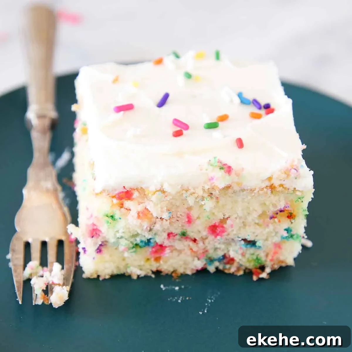 slice of funfetti cake on green plate with vintage fork.