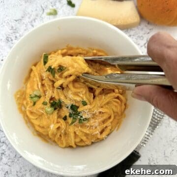 Tongs being used to scoop a serving of pasta.