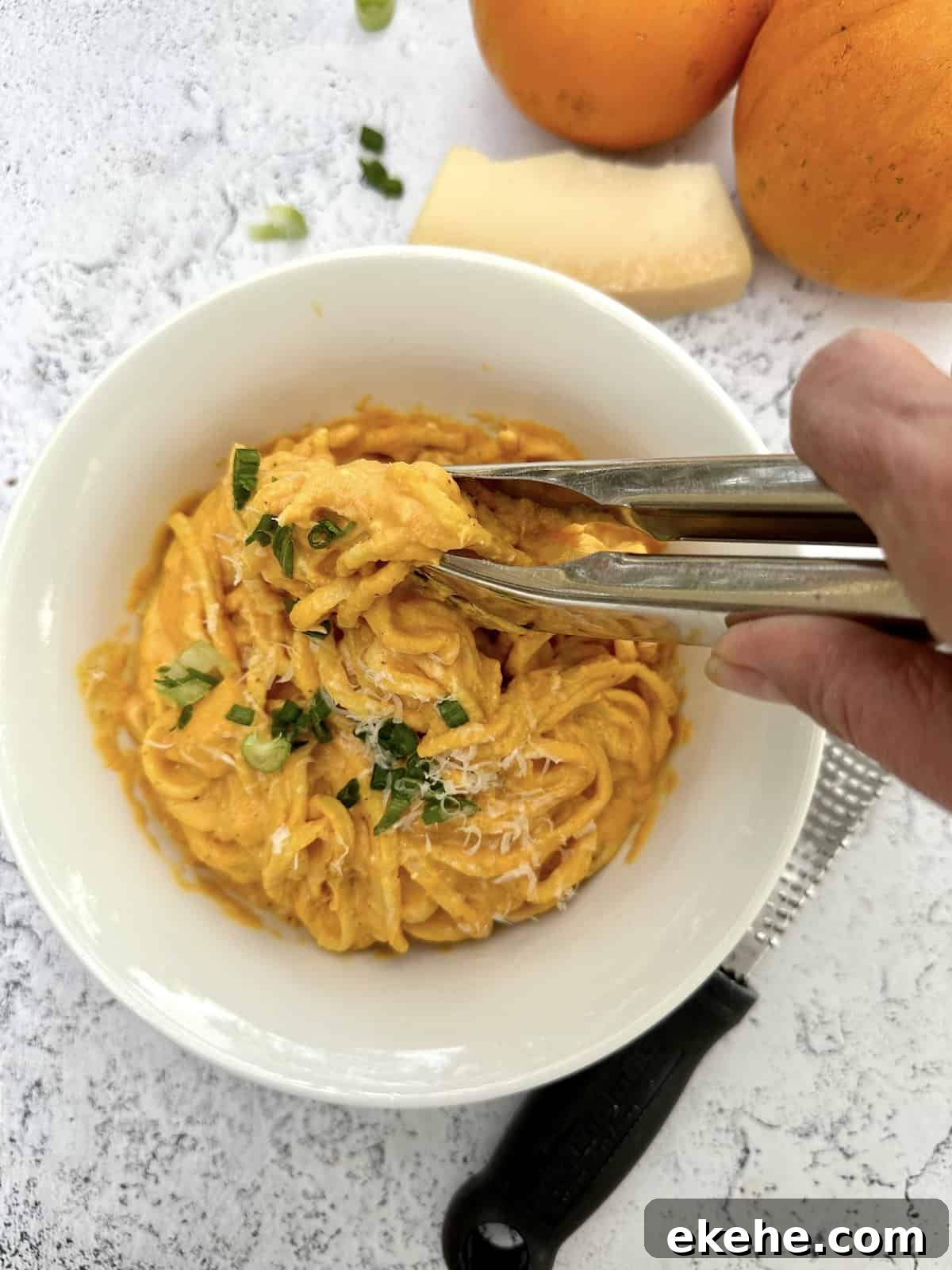 Tongs being used to scoop a serving of pasta.