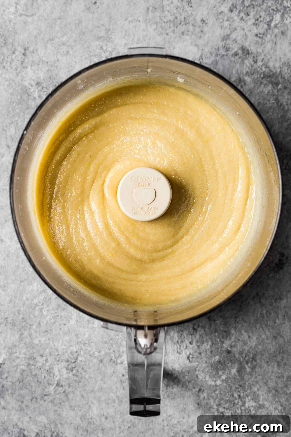 A food processor filled with smooth, golden yellow frangipane.