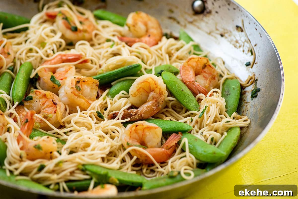 Shrimp, Sugar Snap Pea and Scallion Stir Fry with Miso Sauce in wok on table.