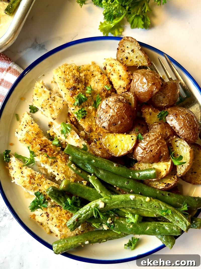 Crispy parmesan chicken plated with potatoes and green beans.