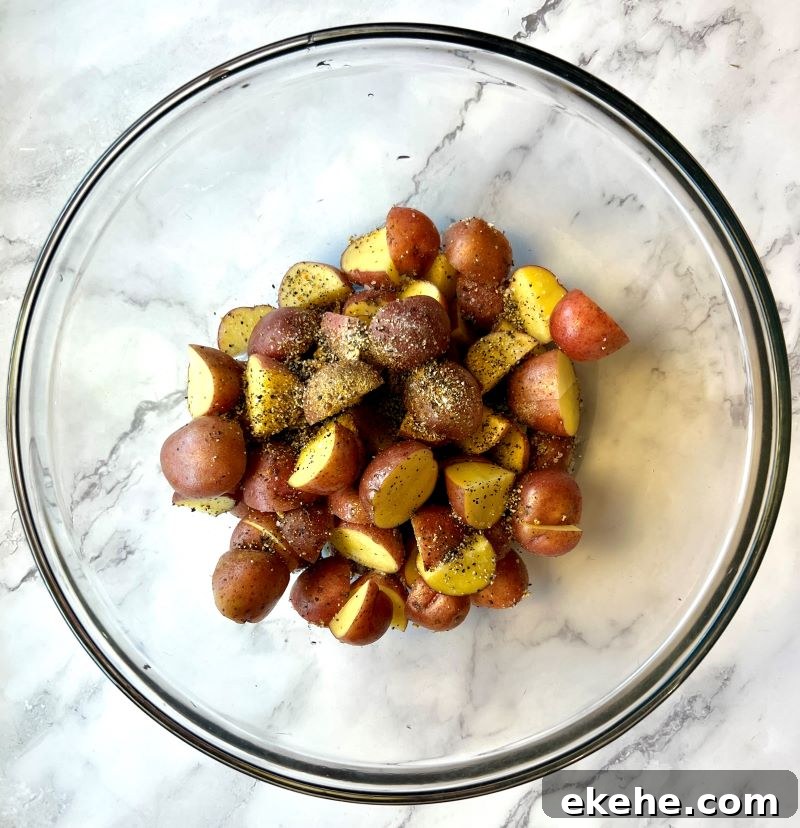 Baby potatoes cut in half in a bowl with lemon pepper, oil, salt and pepper