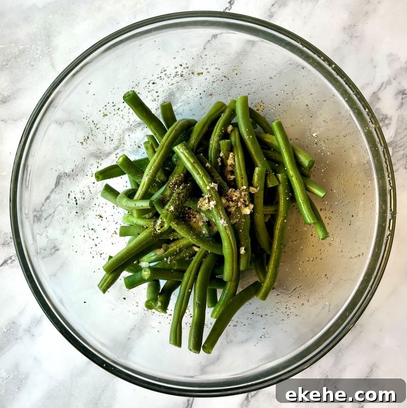 Fresh green beans tossed in a bowl with fresh garlic, oil, salt and pepper.