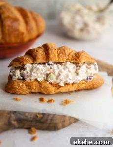 croissant sandwich on wooden board with croissants and chicken salad blurred in background