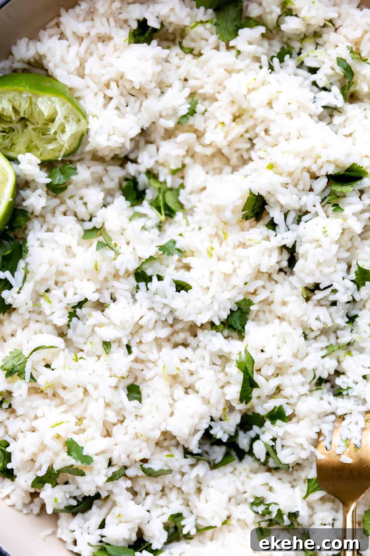 Up close look at cilantro lime rice with specks of fresh cilantro and lime halves that have been juiced.