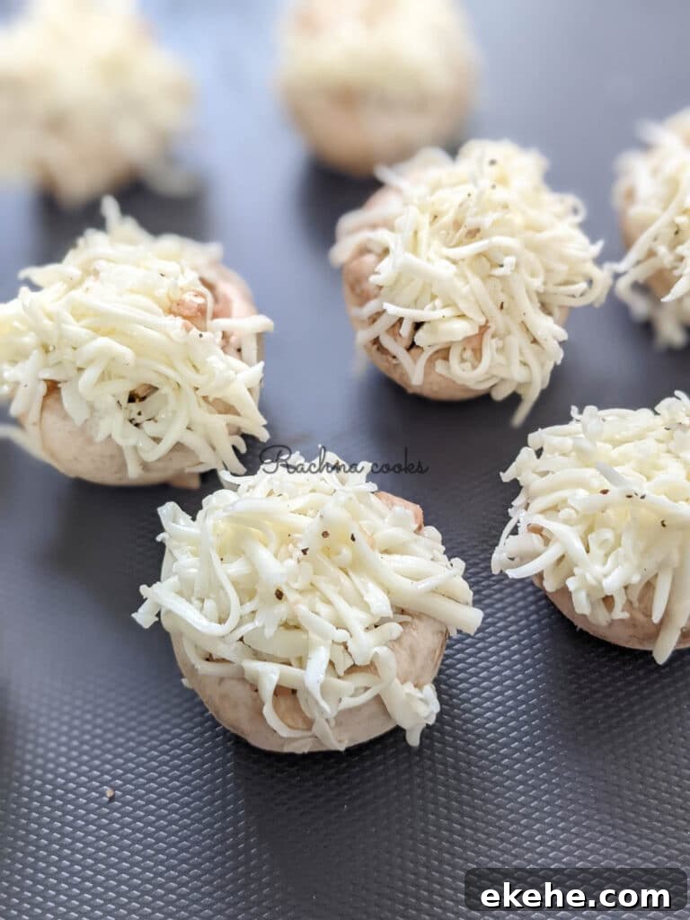 Mushroom caps stuffed and garnished with grated cheese ready for air frying.