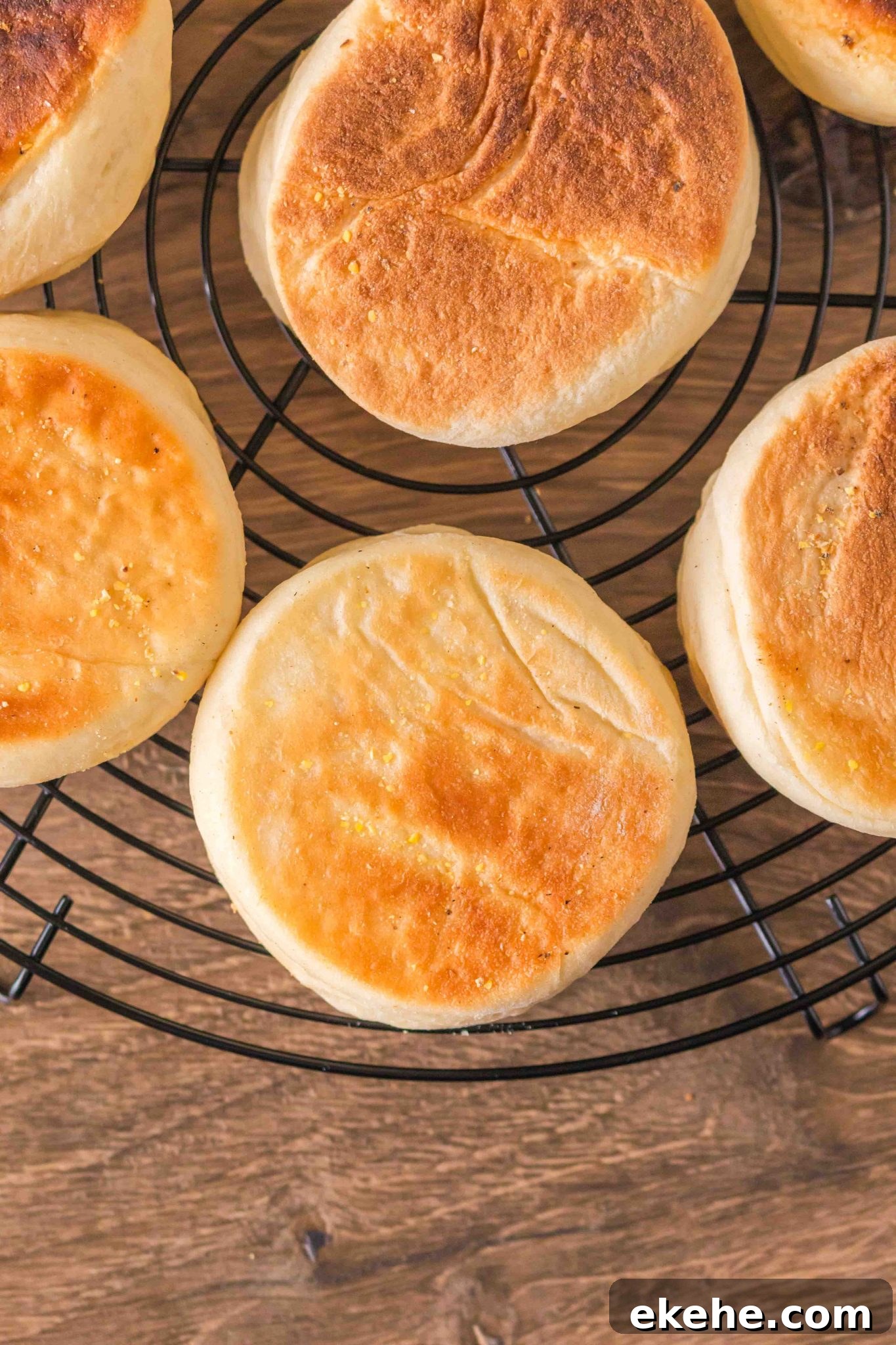 Top down view of golden brown English Muffins on a cooling rack. Hostess At Heart