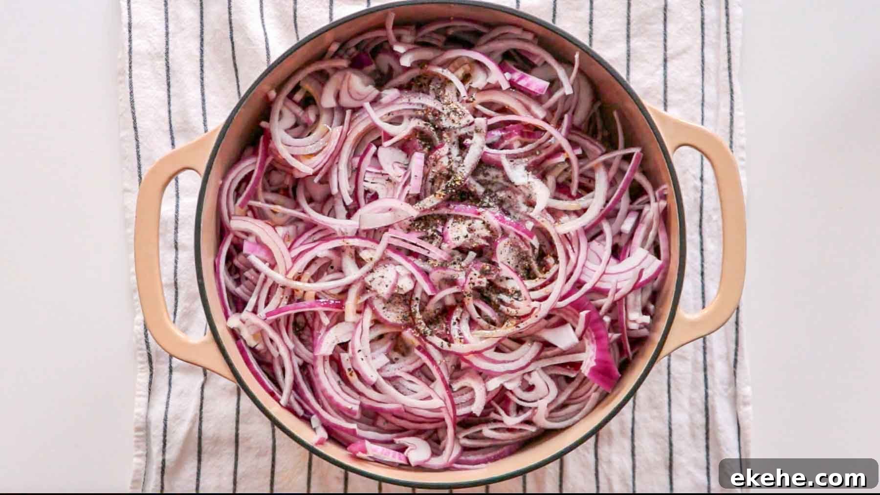 Sliced red onions and black pepper in a dutch oven.