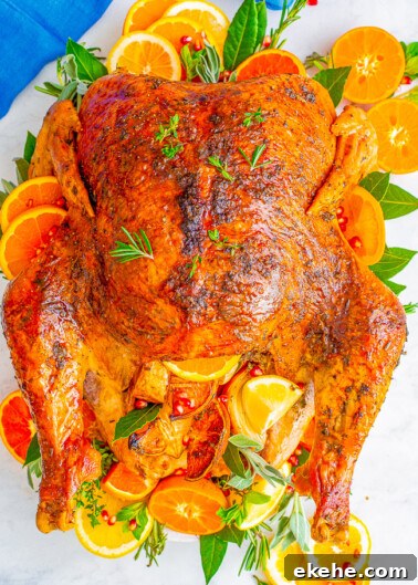 Roasted chicken garnished with slices of orange and herbs on a serving platter.