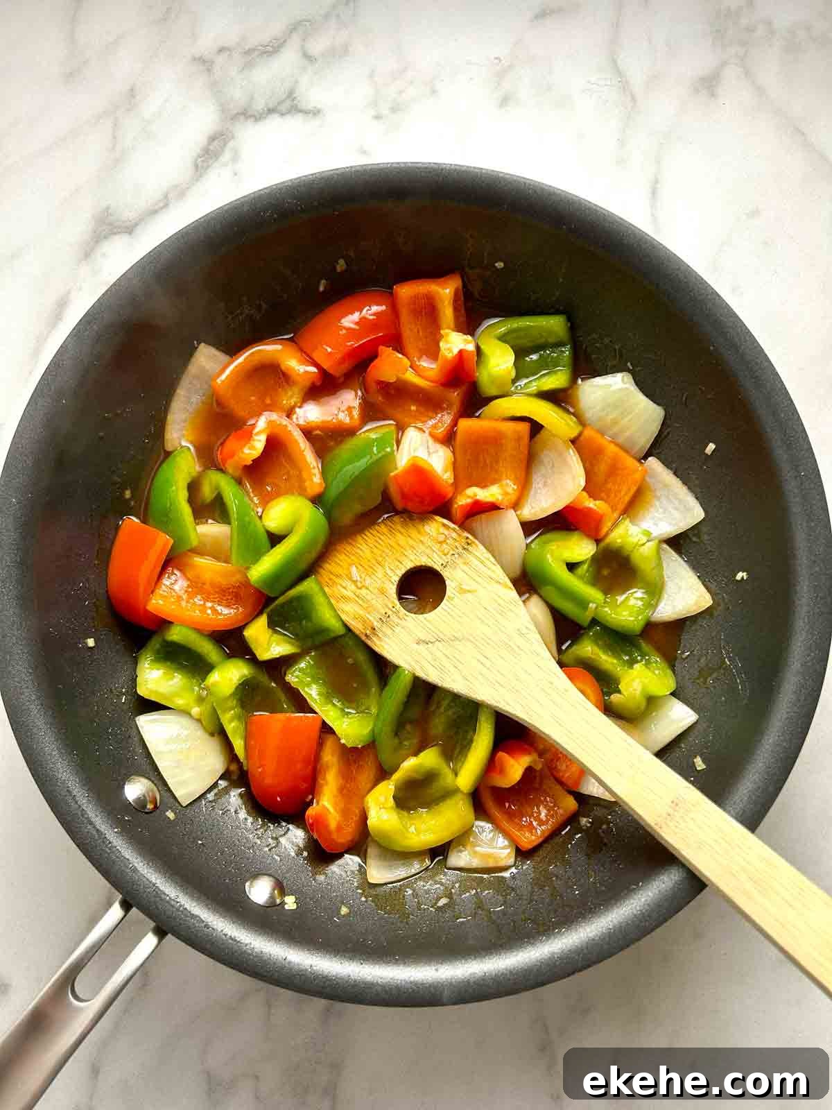 sauce with peppers and onions cooking in pan.