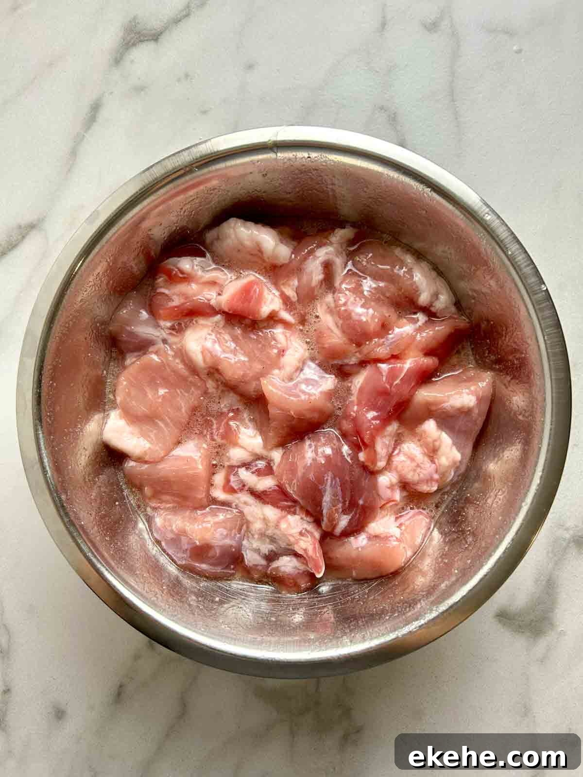 pork pieces being marinated in bowl.