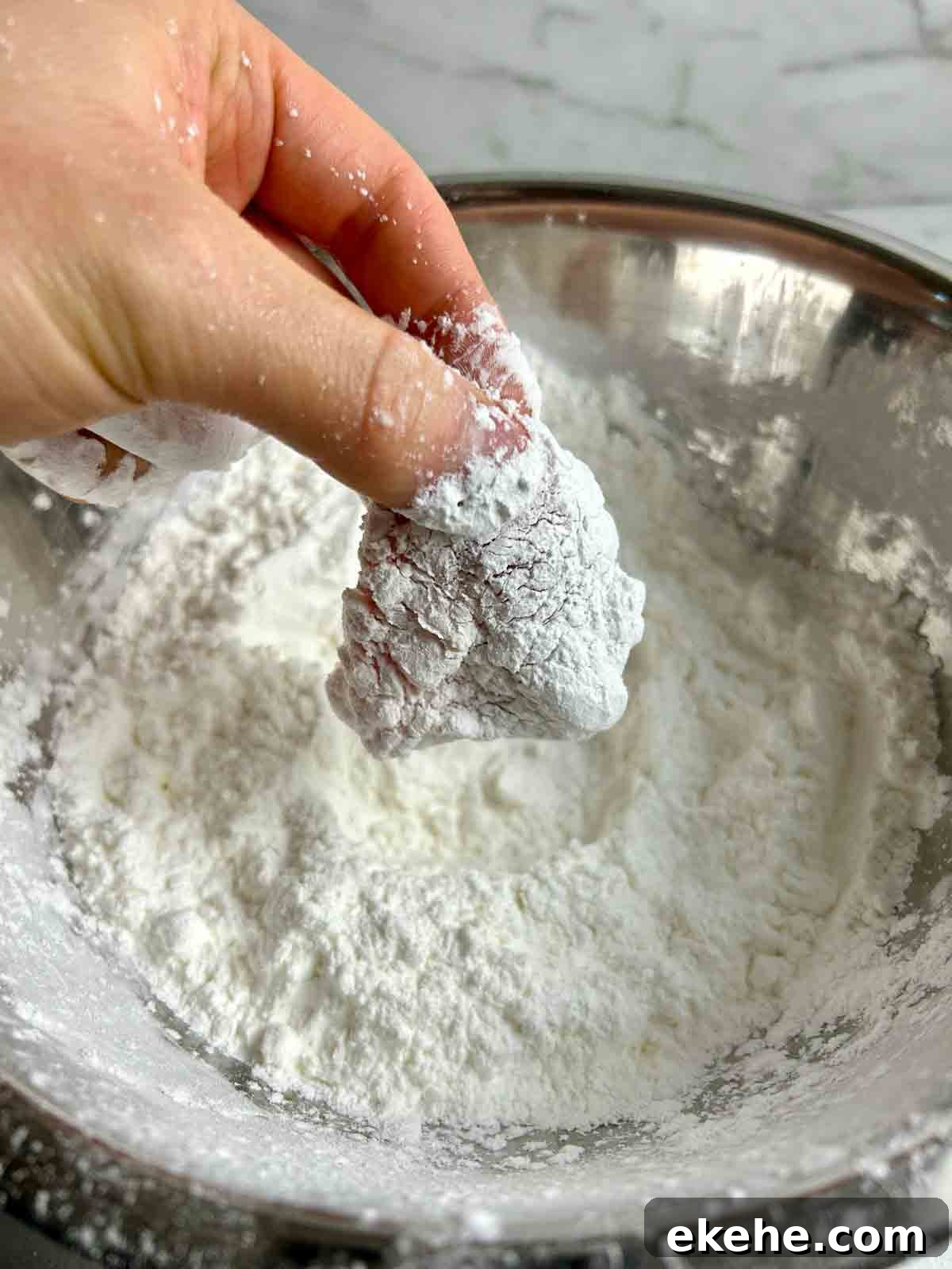 piece of pork being coated in starch mixture.