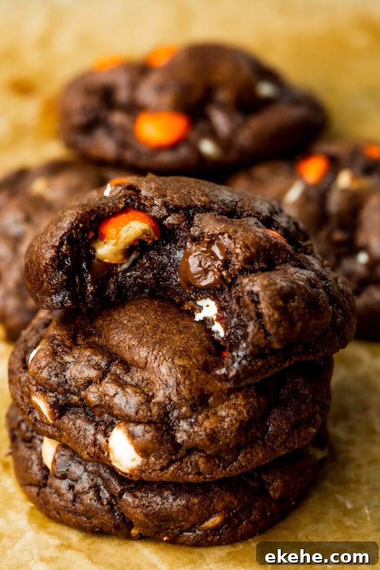a photo of three triple chocolate Reese's cookies stacked on each other with a bite taken out of the top cookie