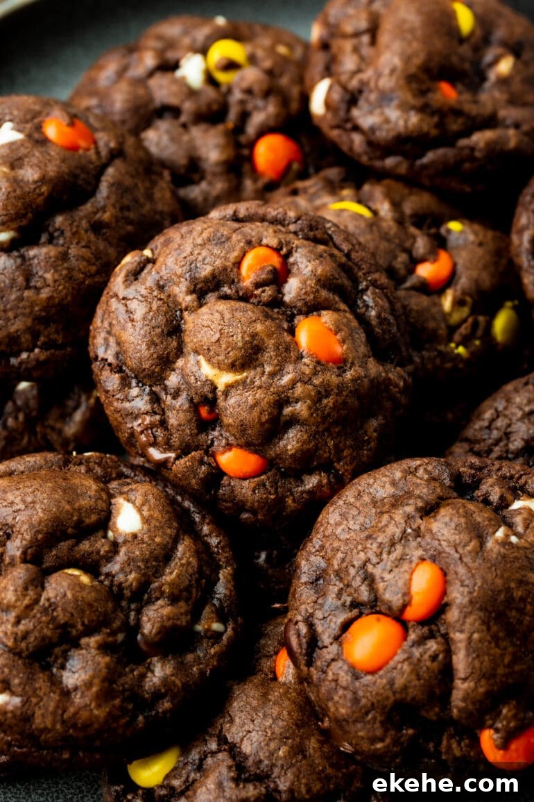 a photo of several thick and chewy Reese's triple chocolate cookies piled on a wire cooling rack