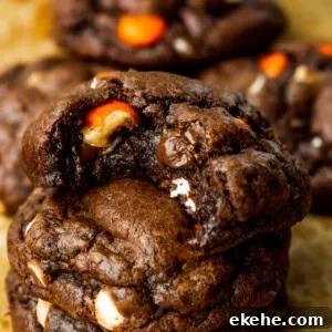 a photo of three triple chocolate Reese's cookies stacked on each other with a bite taken out of the top cookie
