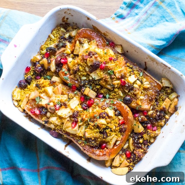 A baking dish filled with two halves of butternut squash stuffed with quinoa, apples and figs.