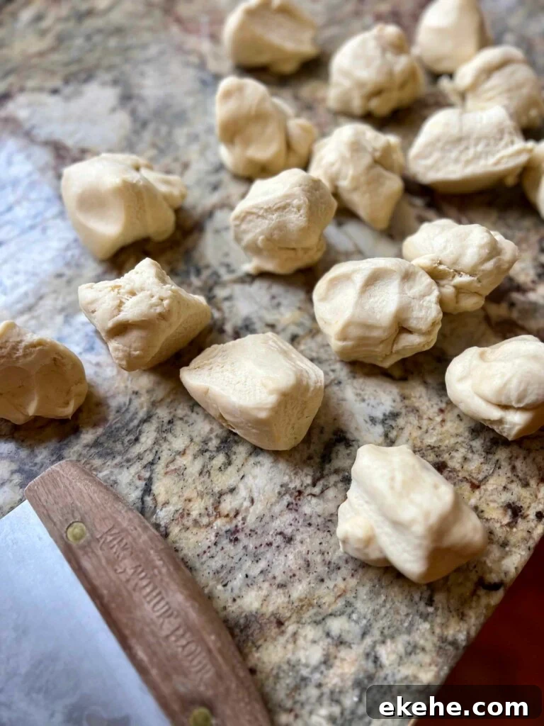 Pieces of sourdough kolache dough divided on a granite countertop with a bench scraper.