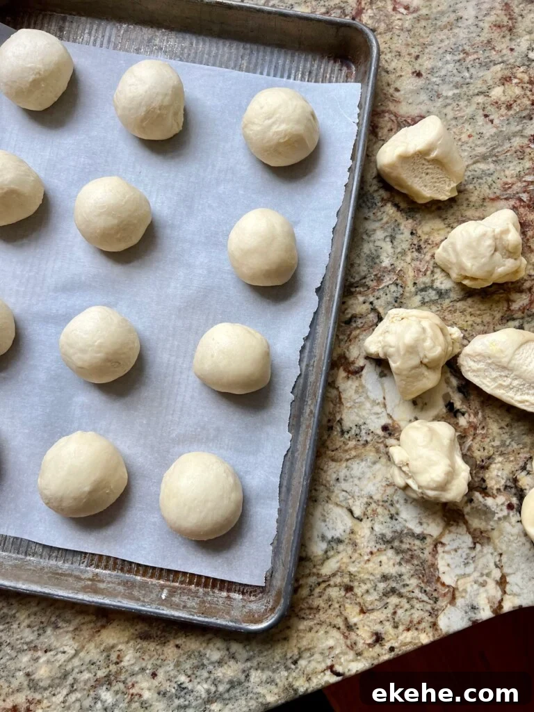 Smooth dough balls for sourdough kolaches arranged on a parchment-lined baking sheet.