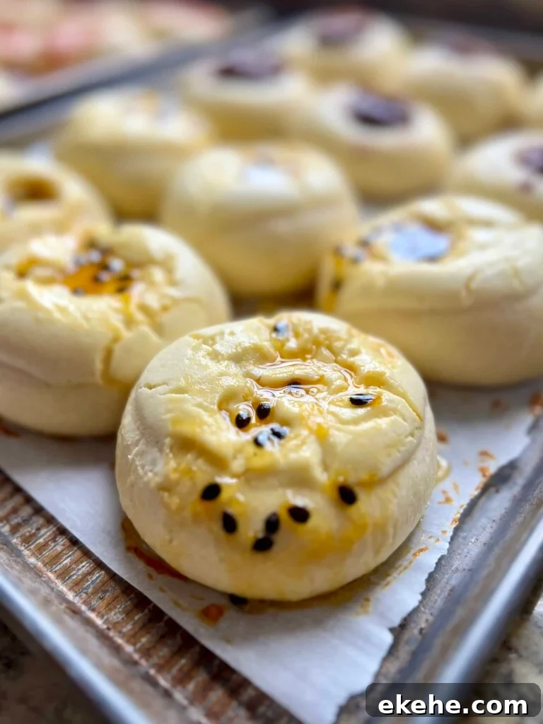 Baked sourdough kolaches topped with passion fruit jam on a sheet pan.