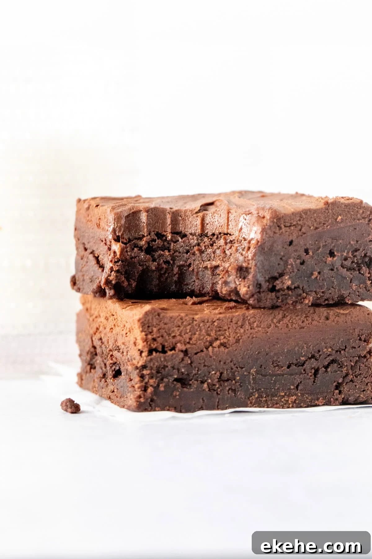 Two chocolate brownies with chocolate brownies, stacked on top of one another with a bite taken out of the top brownie