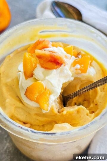 container of creamy peach ice cream with a spoon