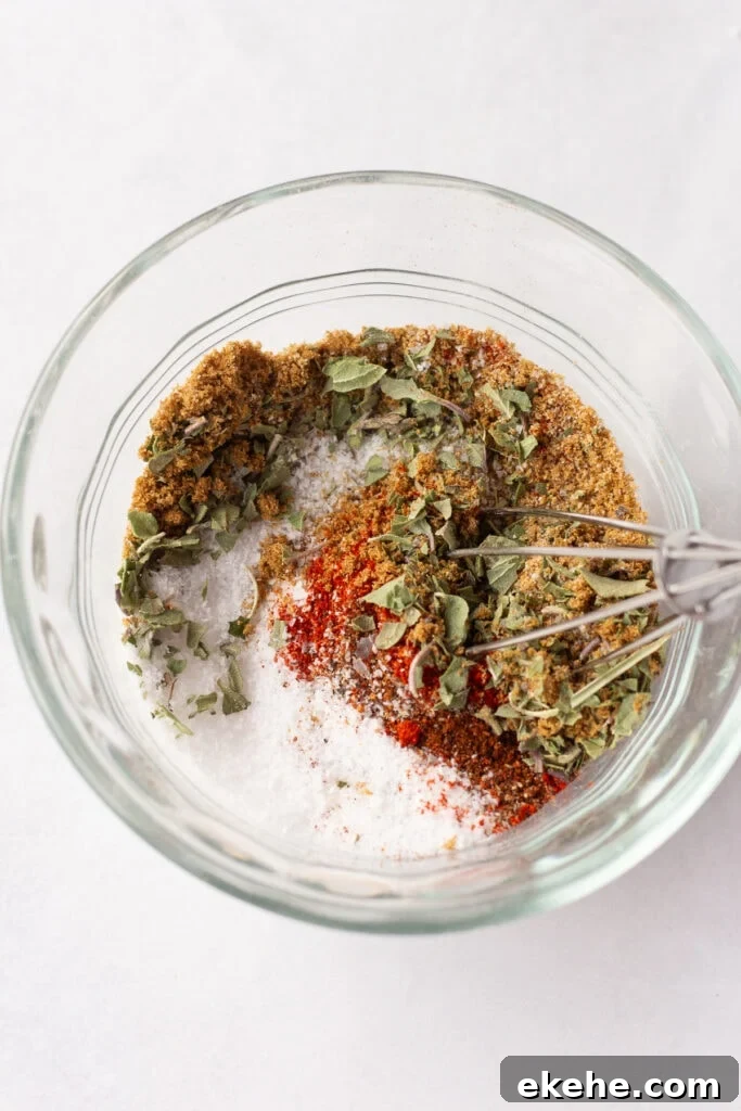 A small glass bowl with spices in it being stirred by a small whisk.