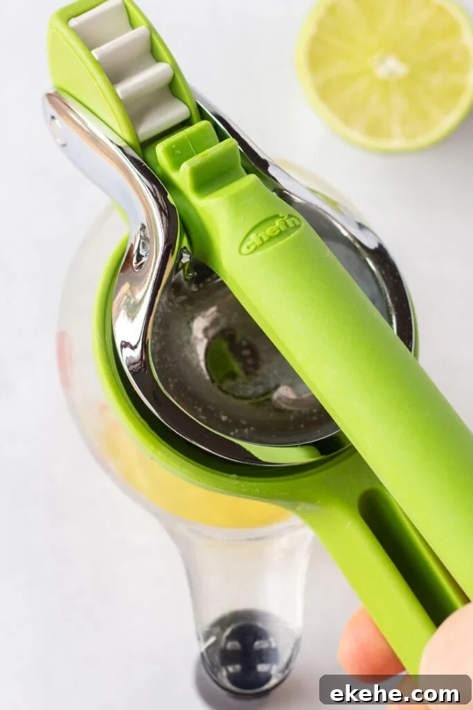 Close up of a lime being juiced into a measuring cup.