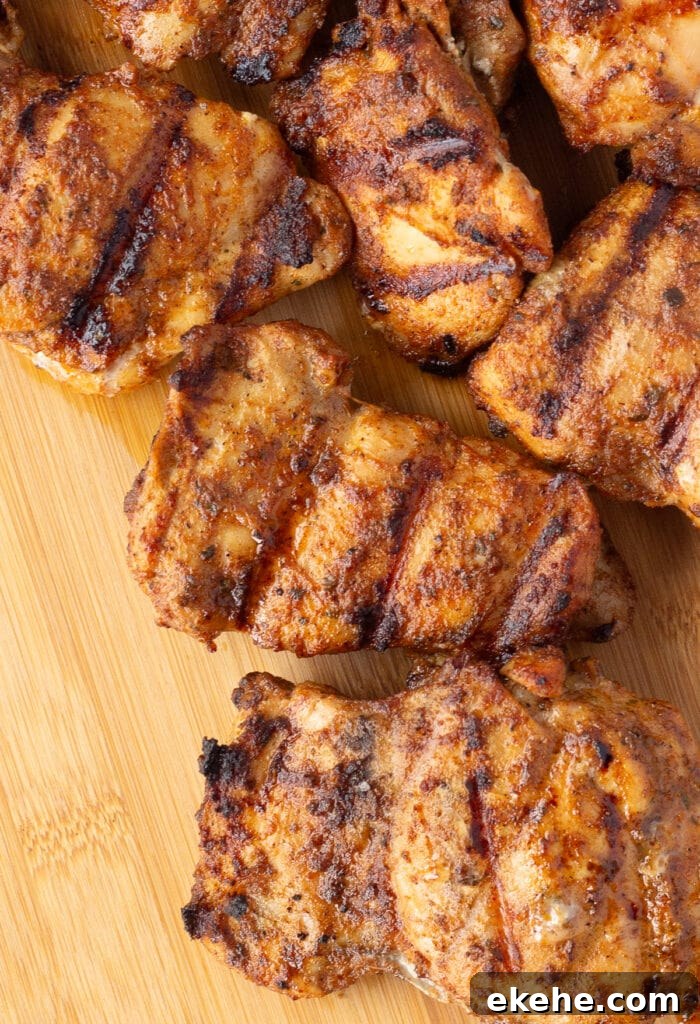 To down shot of grilled chicken thighs on a wood cutting board.