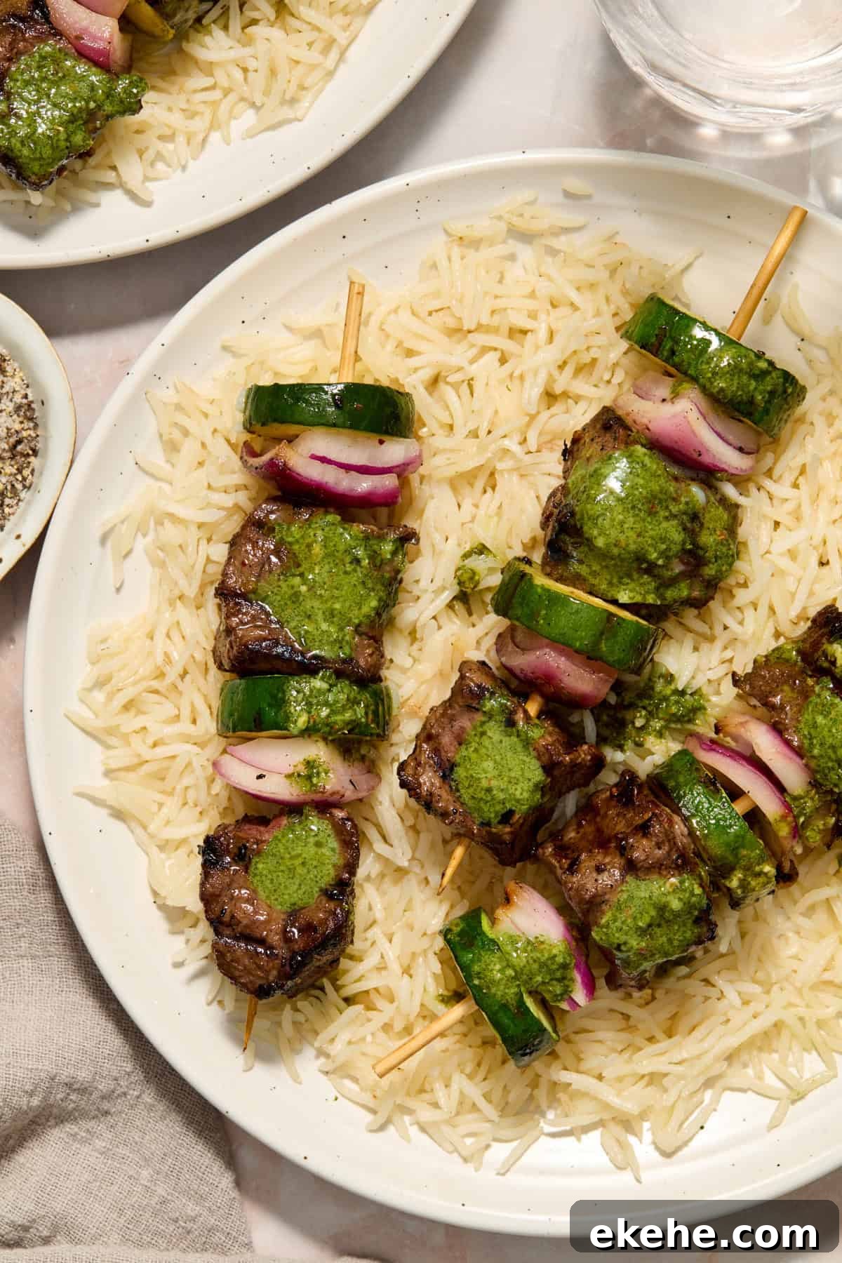 Grilled steak kabobs with zucchini and onion over rice and topped with cilantro chimichurri.