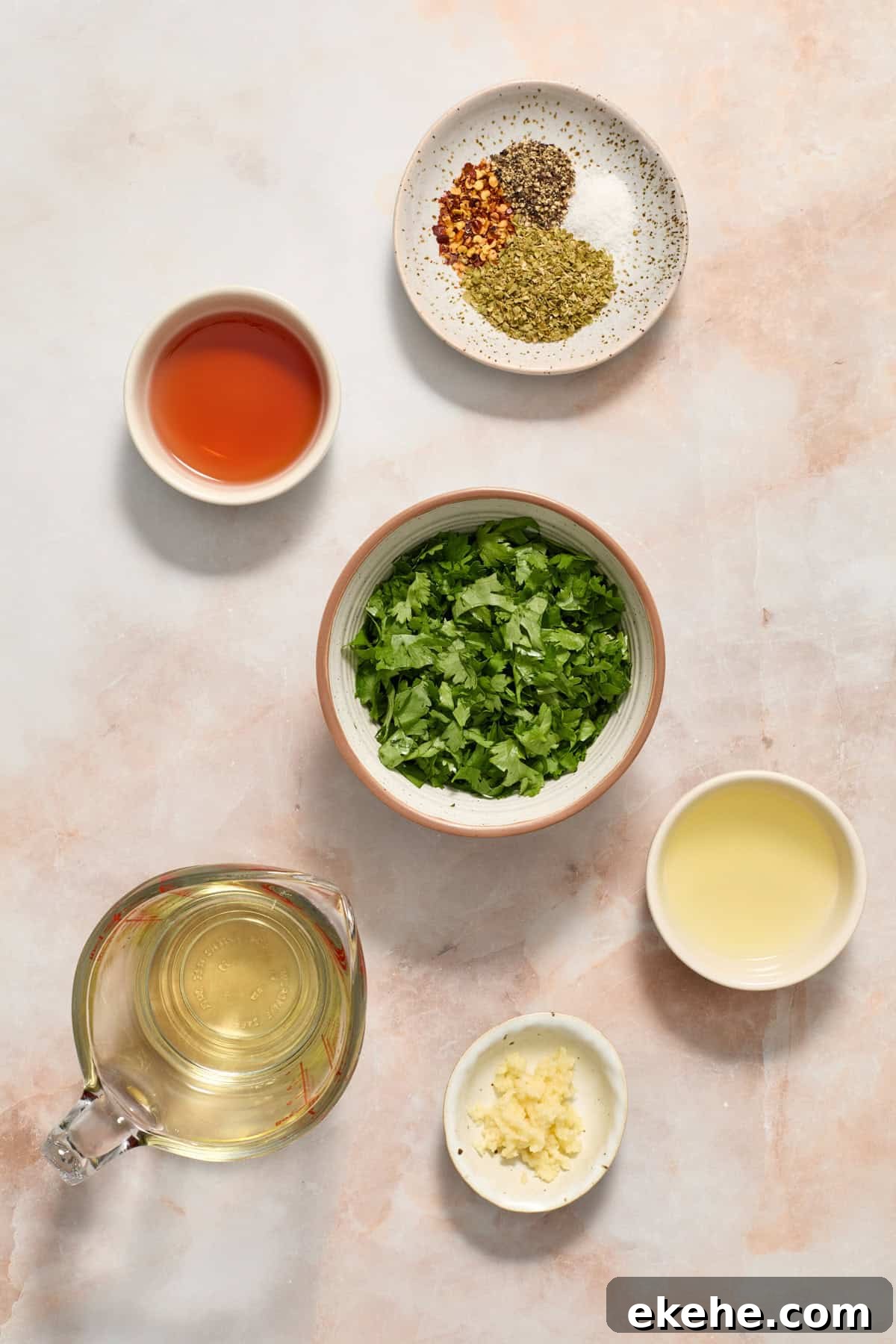 Chopped cilantro, spices, olive oil , garlic and other chimichurri ingredients arranged on surface.