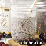 cherry vanilla overnight oats in a mason jar with a gold spoon.