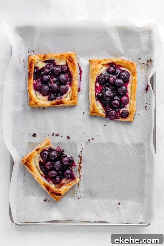 A tray with multiple baked blueberry danishes.