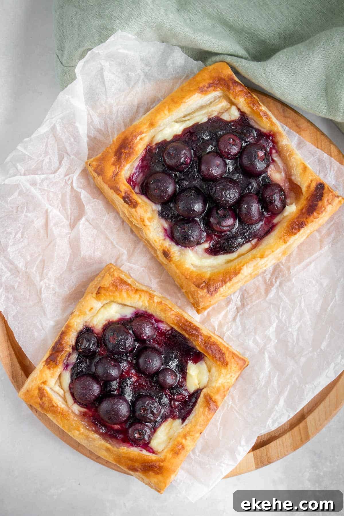 Two blueberry cream cheese danish on a serving board.