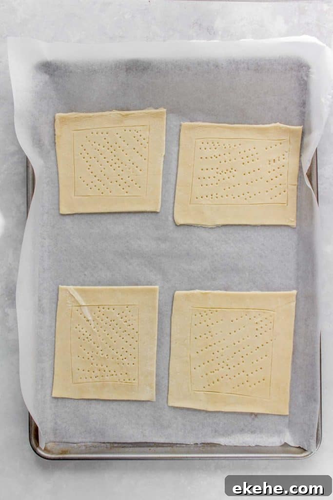 Sheet pan with four piece of puff pastry docked.