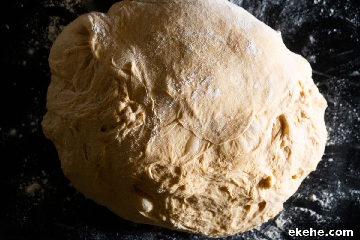 Pumpkin sourdough dough on a black marble pastry slab, after the first proof waiting to be shaped