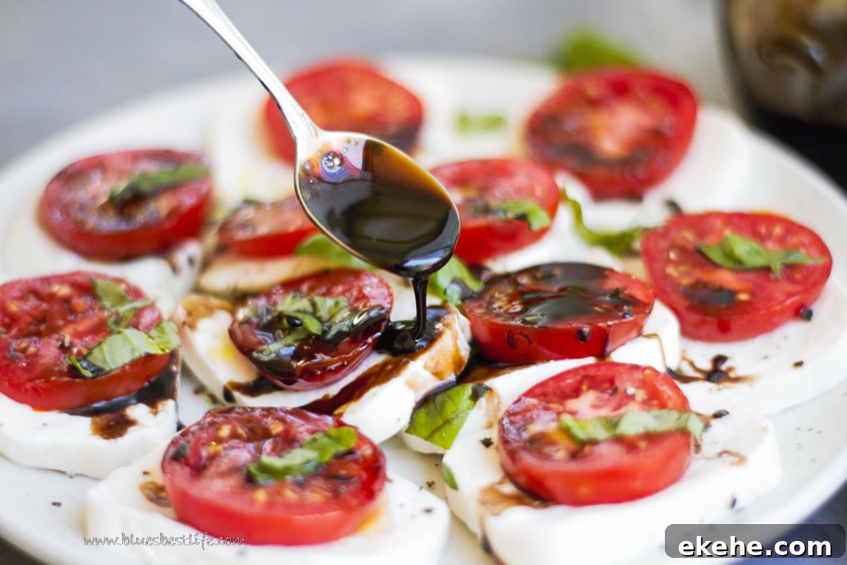 caprese salad with balsamic glaze being drizzled over the top